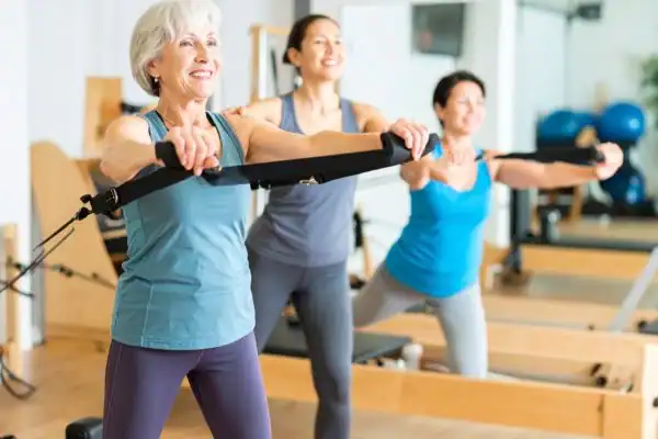 Toning Arms After 60: Empowering Womens Fitness Through Effective Weight Training 2 older woman doing weight training Harefield and resistance in the gym to tone upper arms